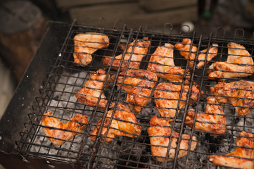 Kebabs chicken wings on the grill with smoke close-up. Chunks of chicken barbecue on the fire. Backyard, concept of rest, meat, summer, copy space.