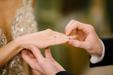 The bridegroom puts the wedding ring on the bride close up. The bride puts the bridegroom on the wedding ring.
