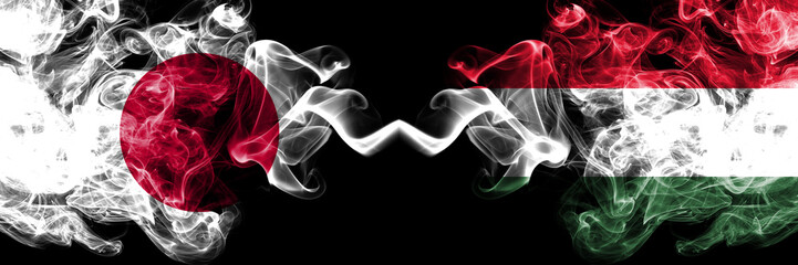 Japan vs Hungary, Hungarian smoky mystic flags placed side by side. Thick colored silky smokes combination of Hungary, Hungarian and Japanese flag