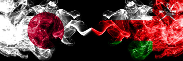 Japan vs Oman, Omani smoky mystic flags placed side by side. Thick colored silky smokes combination of Oman, Omani and Japanese flag