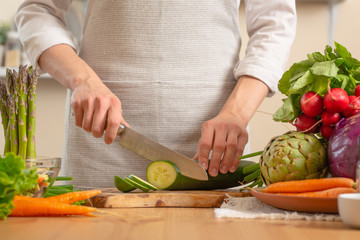 The chef cuts cucumber on a light background. A concept of losing healthy and wholesome food,...
