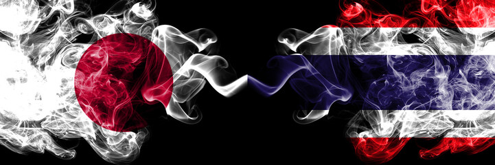 Japan vs Thailand, Thai smoky mystic flags placed side by side. Thick colored silky smokes combination of Thailand, Thai and Japanese flag