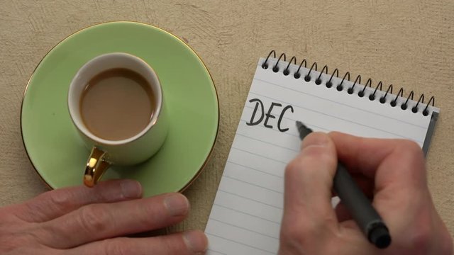 Declutter word - man hand writing a note with a black marker in a spiral notebook, overhead view
