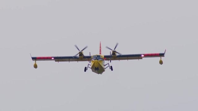 Canadair CL-415 water bomber taking off with retracting  landing gear slow motion. Flying towards camera.
