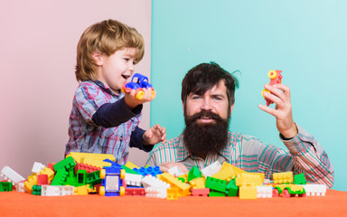 playroom. father and son play game. little boy with bearded man dad playing together. child development. happy family in playroom. leisure time. building home with colorful constructor. playroom game