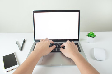 Mockup image of hands are using a white screen laptop, desk in office.