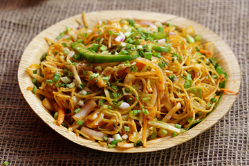 Schezwan Noodles or vegetable Hakka Noodles or chow mein is a popular Indo-Chinese recipes, served in a bowl or plate 