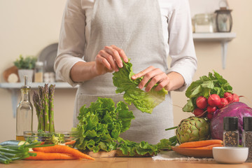 Chef cuts fresh green salad. The concept of losing healthy and wholesome food, detox, vegan eating, diet, cooking. Slow food, comfort food, clean food