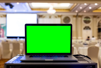 Laptop with blank green screen in seminar room.