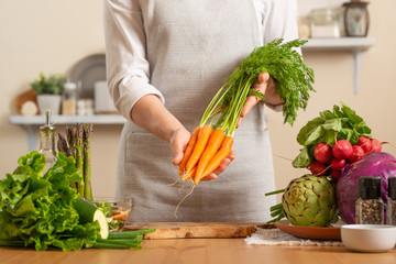 Chef is holding a fresh carrot. The concept of losing healthy and wholesome food, detox, vegan eating, diet, cooking. Slow food, comfort food, clean food