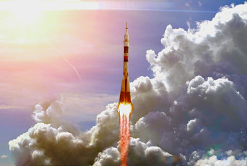 Dramatic launch. Rocket launching. Blue sky. CLouds and sun flare. Elements of this image furnished...