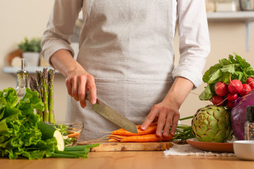 The chef cuts fresh carrots for salad. The concept of losing healthy and wholesome food, detox, vegan eating, diet, cooking. Slow food, comfort food, clean food