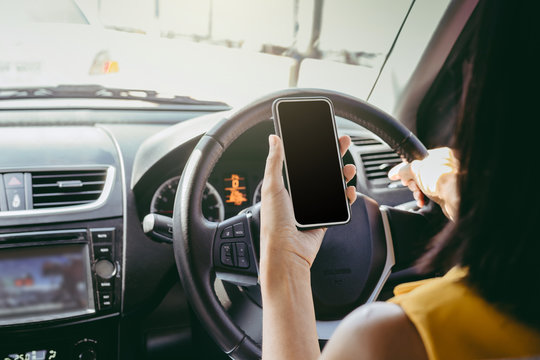 Young woman sitting in car and using her smartphone. Mock up image with phone screen.