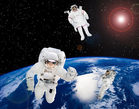Earth and astronauts in space suits in outer space. Space walk. The elements of this image furnished by NASA.