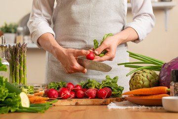 Chef cuts fresh radish for salad. The concept of losing healthy and wholesome food, detox, vegan eating, diet, cooking. Slow food, comfort food, healthy diet, clean eating, horizontal photo