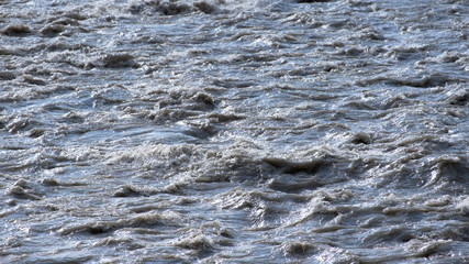 Dirty water in a stormy river. The texture of the water. No people. The rapid flow of the mountain river.