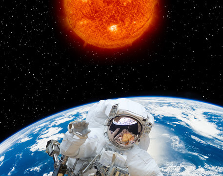 Big sun and astronaut flying in the space. The elements of this image furnished by NASA.