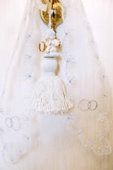 An angel holding two golden wedding rings. Wedding lace background.