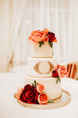 White wedding cake decorated with red roses.  