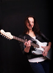 Obraz premium Beautiful dark girl playing guitar in rock style on a black background.