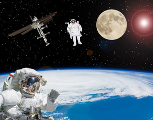 Astronauts flying in outer space. Moon on the backdrop. Space scene. The elements of this image...
