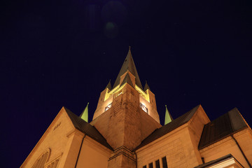 Wieża kościoła nocą na tle niebieskiego nieba z gwiazdami.
