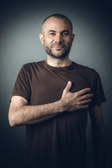 portrait of a man with his hand on his chest, positive and smiling expression