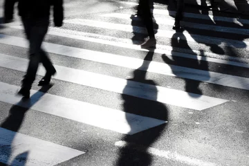 Fototapete Blurry zebra crossing with pedestrians making long shadows © Aleksandra