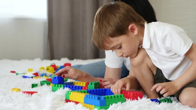 Mother and child resting lying on the bed. Happy family playing with meccano color blocks.
