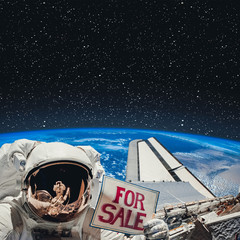 Astronaut above earth with sign "For sale". The elements of this image furnished by NASA.