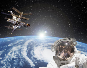 Astronaut, space station and sunrise on the backdrop. The elements of this image furnished by NASA.
