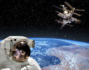 Astronaut looks at the space station. The elements of this image furnished by NASA.
