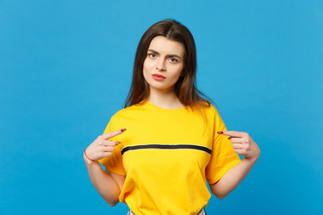 Portrait of dissatisfied young woman in vivid casual clothes looking camera, pointing index fingers...