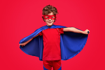 Cheerful superhero spreading cape