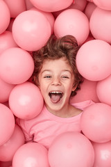 Fototapeta na wymiar Excited kid playing in balloons