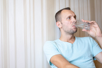 Fototapeta na wymiar the guy is drinking clean glass water