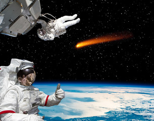 Astronaut gives thumbs-up, comet on the background. The elements of this image furnished by NASA.