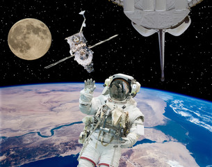 Astronaut in outer space, moon and spaceships on the backdrop. The elements of this image furnished...