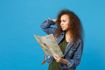 Young african american girl teen student in denim clothes, backpack hold map isolated on blue wall background studio portrait. Education in high school university college concept. Mock up copy space.