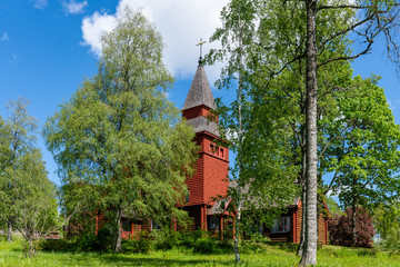 Old red wooden church in summer sunlight