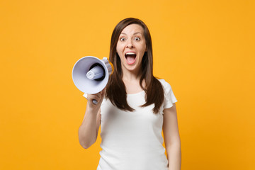 Portrait of excited young woman in white casual clothes keeping mouth open scream in megaphone...