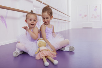 Happy little ballerinas having fun at ballet dance class, copy space. Charming little ballerina girl and her sister exercising at ballet school