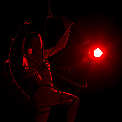 silhouette of sexy woman in red light on a dark background. leggy woman in a bodysuit with metal rings