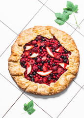 Mixed berries summer pie on a light background, top view. Red, black currant, strawberry, raspberry sweet pie