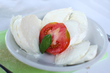 Cut of mozzarella with tomato e leaves of basil.