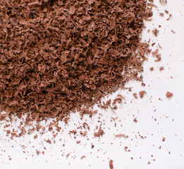 Grated chocolate pn the white background, view from above