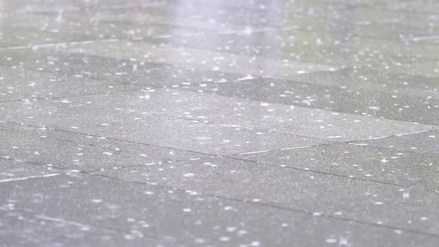 Rain water drops falling into puddle on asphalt, flooding the street. Road floods due to the heavy rain in wet season, super slow motion, heavy rain fall background.