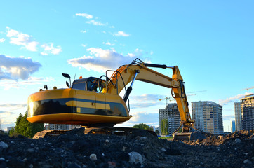 Large tracked excavator digs the ground for the foundation and construction of a new building in the city. Road repair, asphalt replacement, renovating a section of a highway, bridge construction