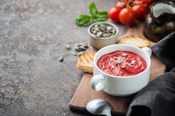 Healthy tomato soup in a white bowl with cream and sunflover seeds