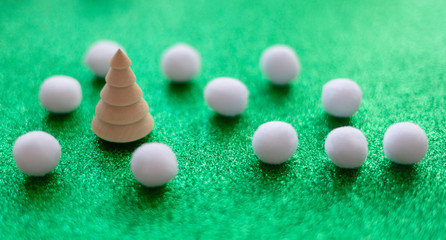 Glitter green sparkle background with wooden Christmas tree and white pompons